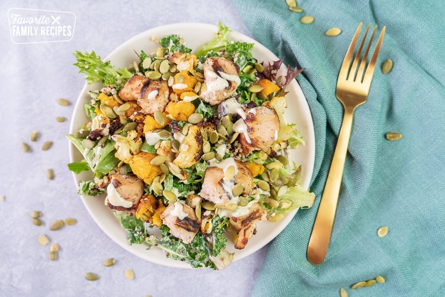 A chicken salad on a white plate with a gold fork.