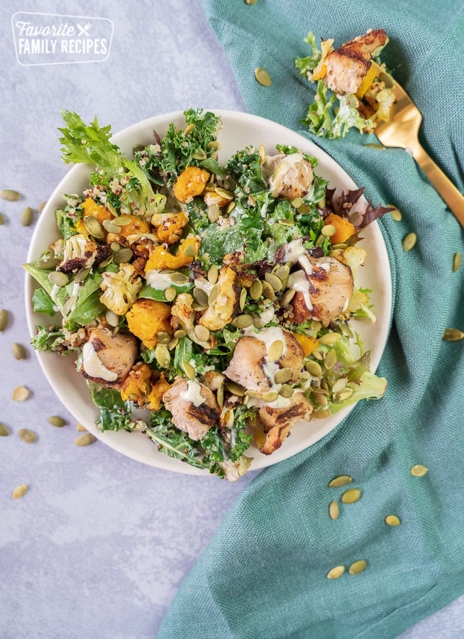 A roasted chicken salad on a plate with a gold fork