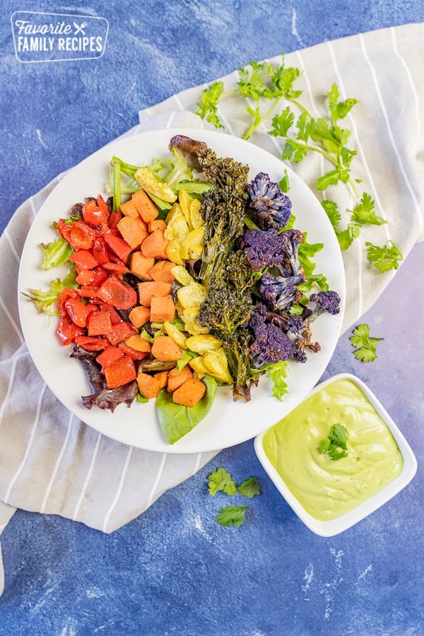 This Buddha Bowl in the colors of the rainbow is the perfect way to add a variety of vegetables to your diet. You will love the creamy avocado dressing! Rainbow Buddha bowl with red, orange, yellow, green, and purple vegetables.