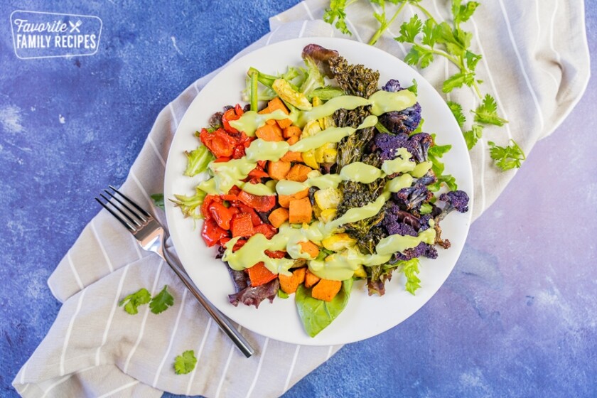 A rainbow Buddha bowl drizzled with dressing.