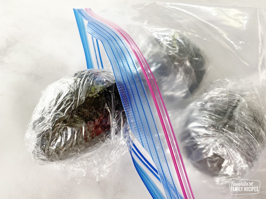 Whole avocados wrapped in plastic wrap