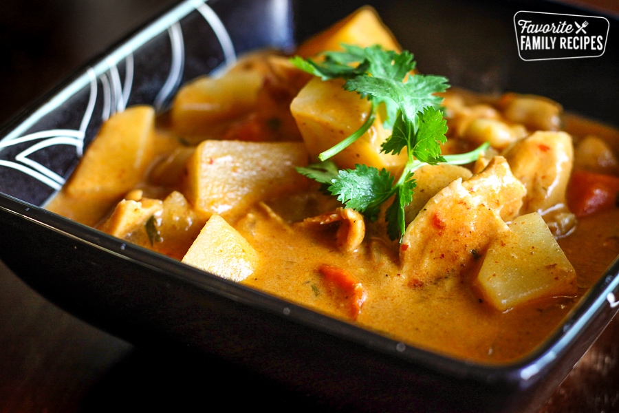 Chicken Massaman Curry with potatoes in a square black dish.