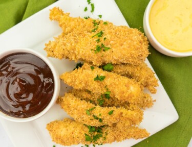 Crispy baked chicken tenders on a white plate.