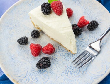 A slice of no bake cheesecake with berries on the side