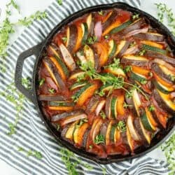 Ratatouille in a cast iron pan with a black and white striped napkin.