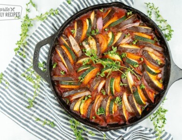 Ratatouille in a cast iron pan with a black and white striped napkin