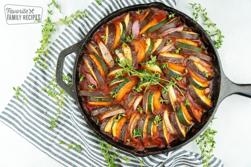 Ratatouille in a cast iron pan with a black and white striped napkin.