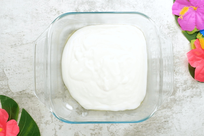 Authentic Hawaiian Haupia (Coconut Pudding) poured into a greased square baking dish.