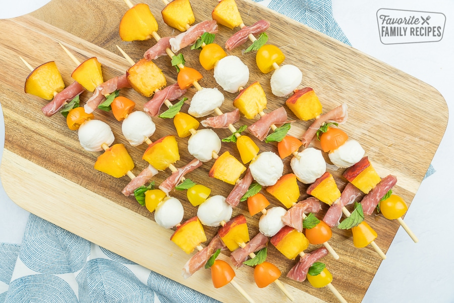 Caprese salad skewers on a wooden cutting board.