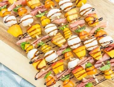 Peach Caprese Salad Skewers on a wood board