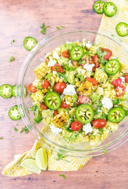 Grilled corn salad in a clear bowl with a yellow napkin underneath