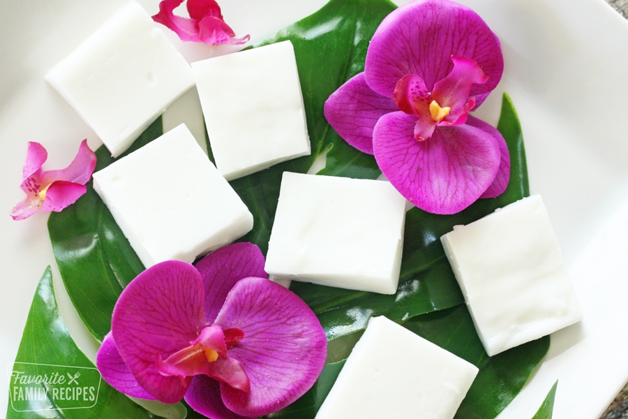 Haupia squares on a leaf on a plate with orchid flowers