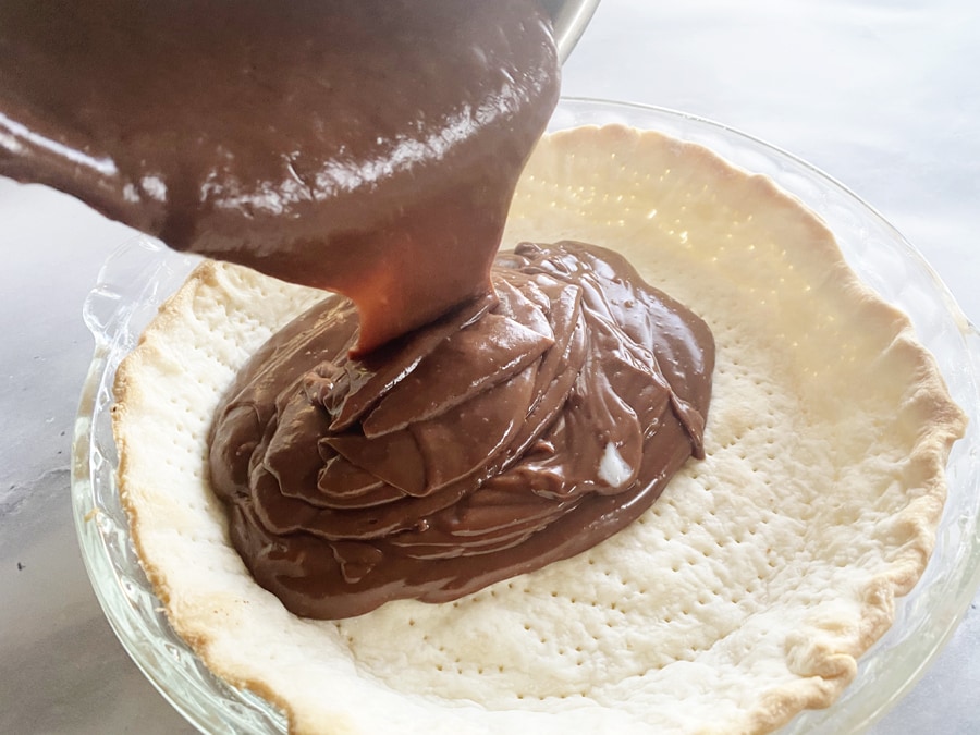 chocolate haupia being poured into a baked pie shell
