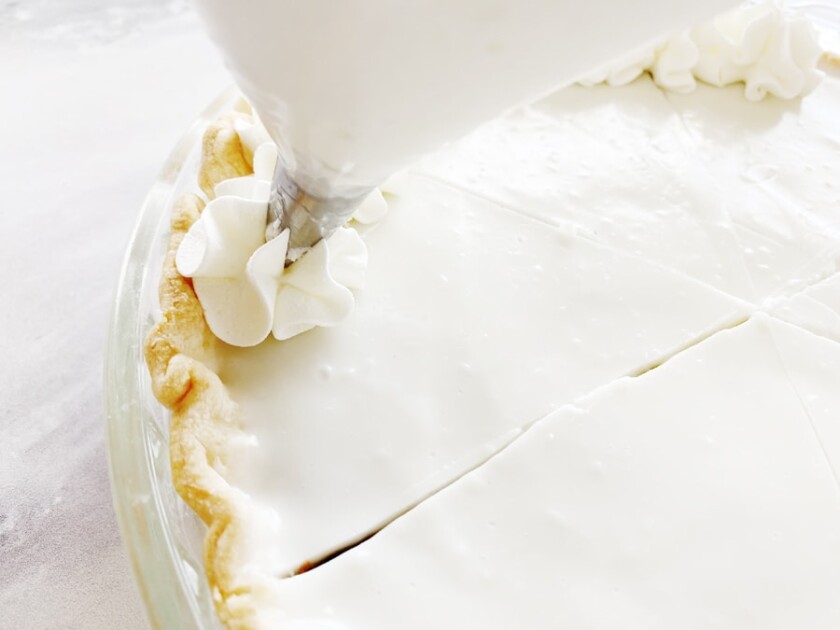 Piping whipped cream onto haupia pie