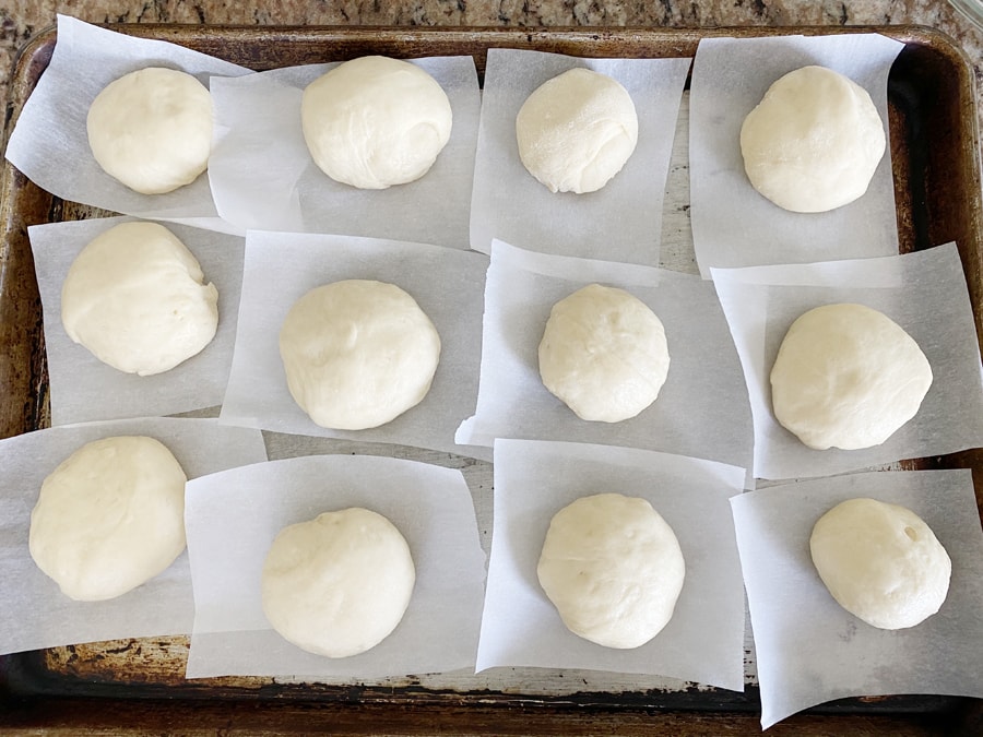 malasada dough balls on parchments paper, ready to rise