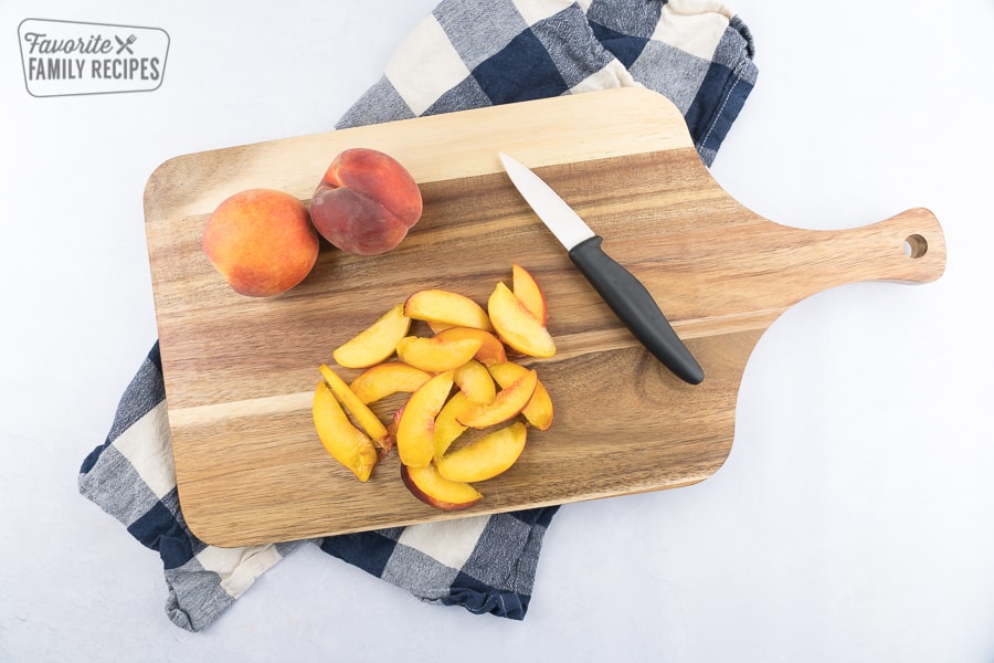 Sliced peaches on a cutting board with a knife.