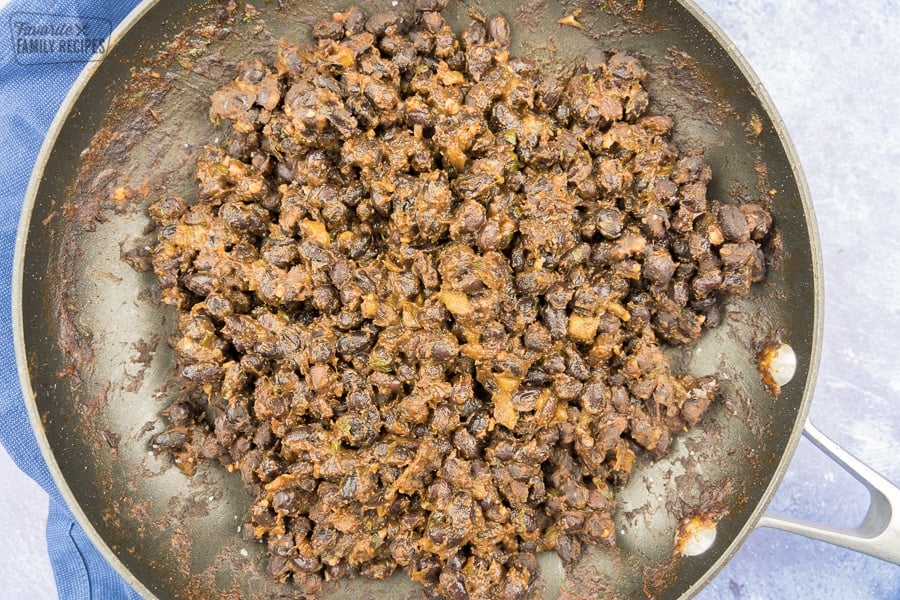 Refried black beans in a black skillet.