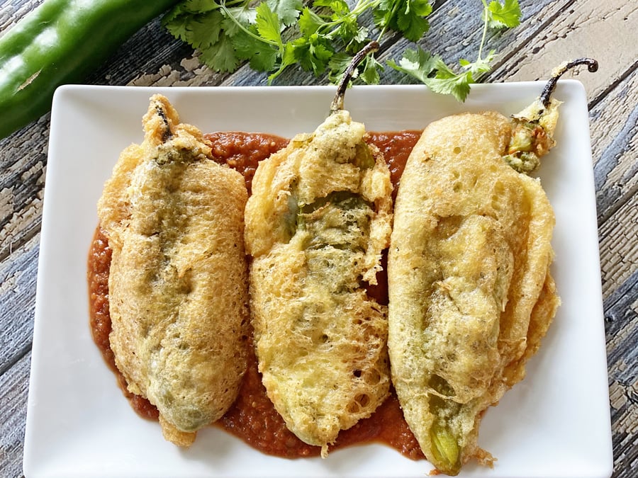 Chile rellenos on a plate with sauce