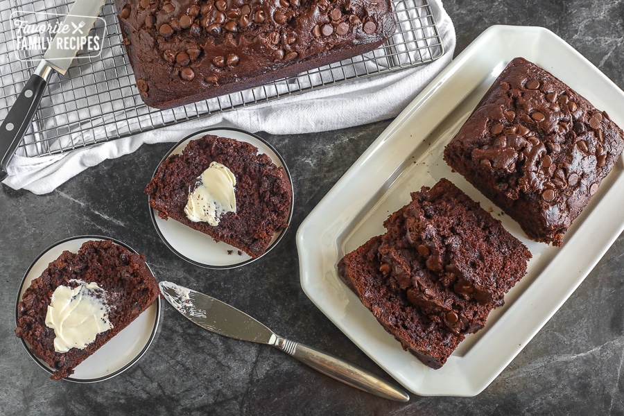 Two loaves of chocolate zucchini bread, one is sliced with a knife to the side.