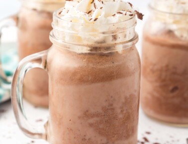 A mug of frozen hot chocolate topped with whipped cream and chocolate shavings