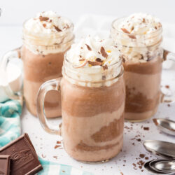 Three mugs of frozen hot chocolate topped with whipped cream and chocolate shavings