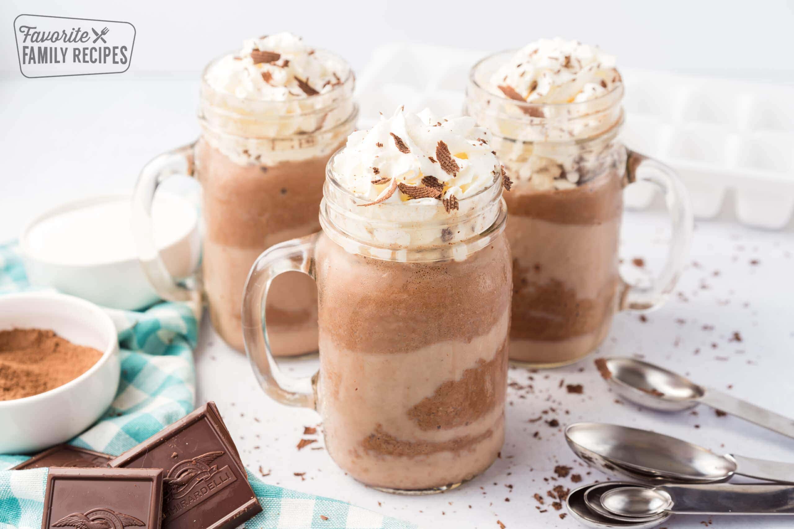 Three mugs of frozen hot chocolate topped with whipped cream and chocolate shavings