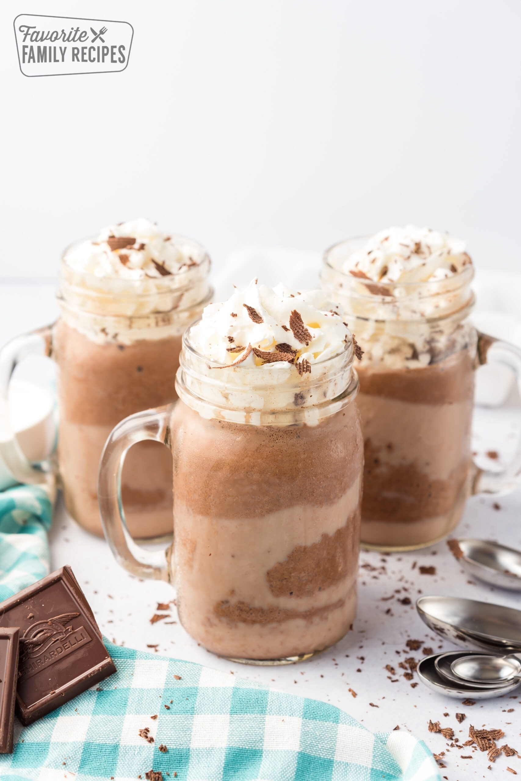 three mugs of frozen hot chocolate with whipped cream and chocolate shavings