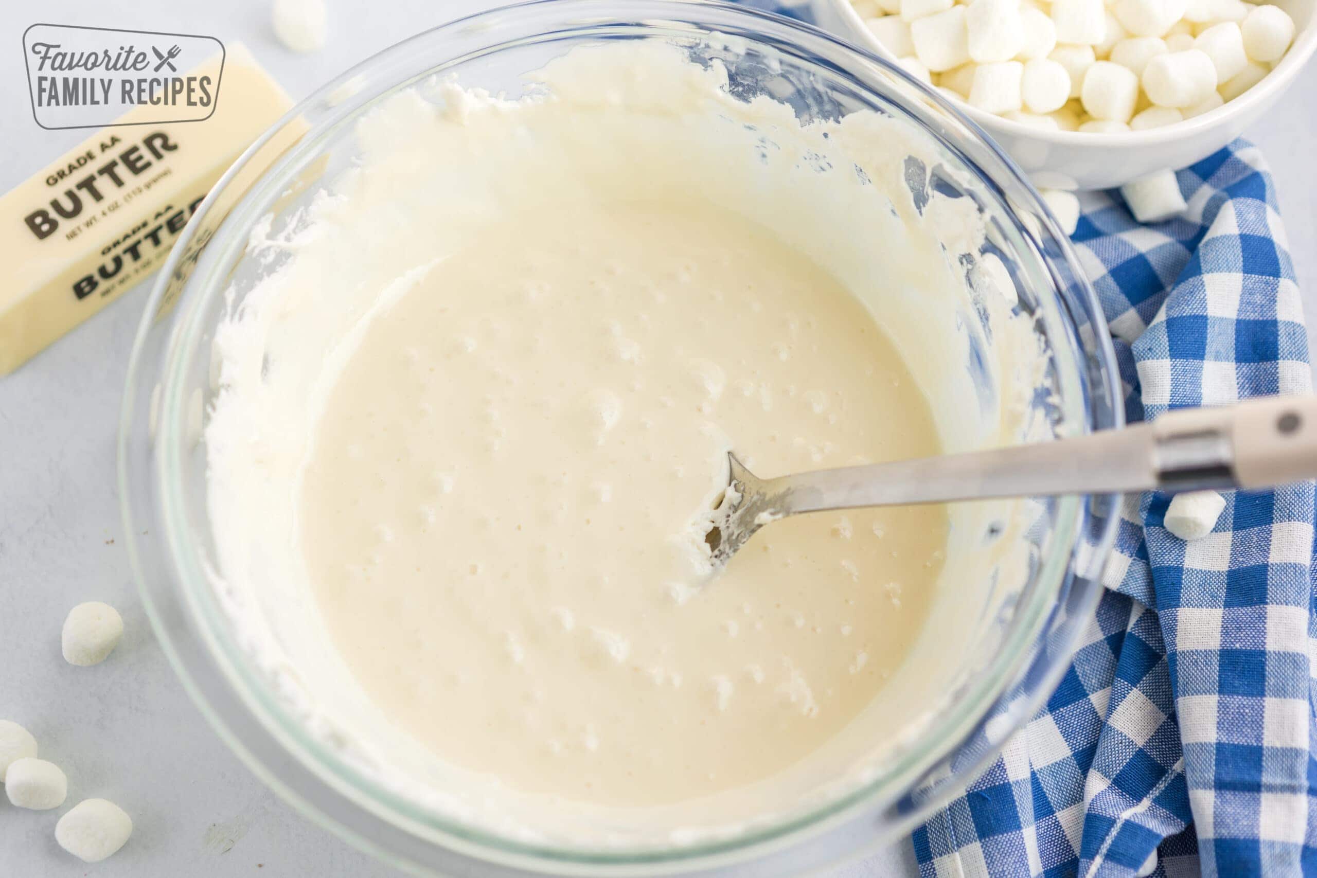 Marshmallows mixture in a glass bowl with a silver spoon in it.