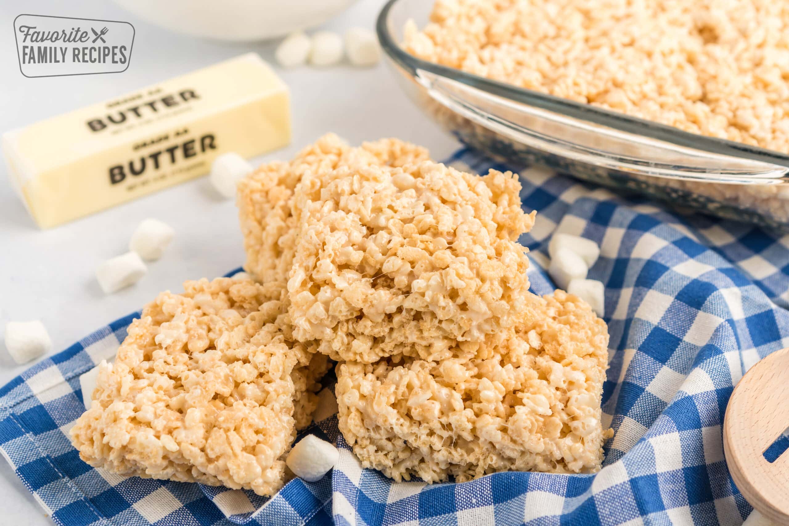 Three rice krispie treats stacked up on a blue checkered cloth.