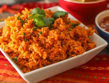 Mexican Rice in a serving bowl with a side of chips and salsa.