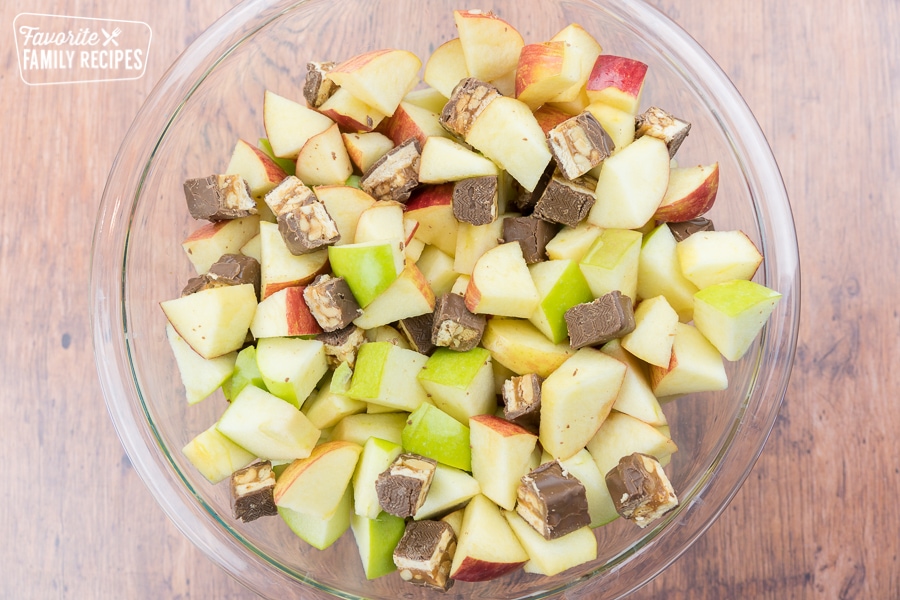 Snickers and sliced apples in a glass bowl.