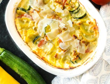 Yellow squash, zucchini, and tomatoes layered in a casserole dish.