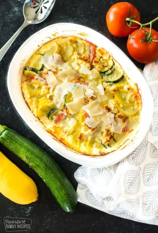 Yellow squash, zucchini, and tomatoes layered in a casserole dish.