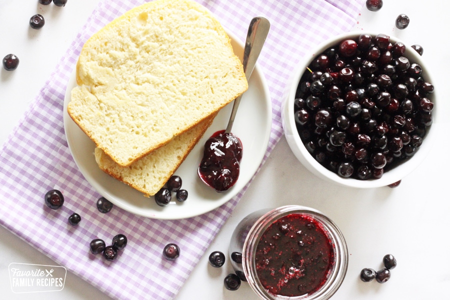 Huckleberries and huckleberry jam next to fresh sliced bread.