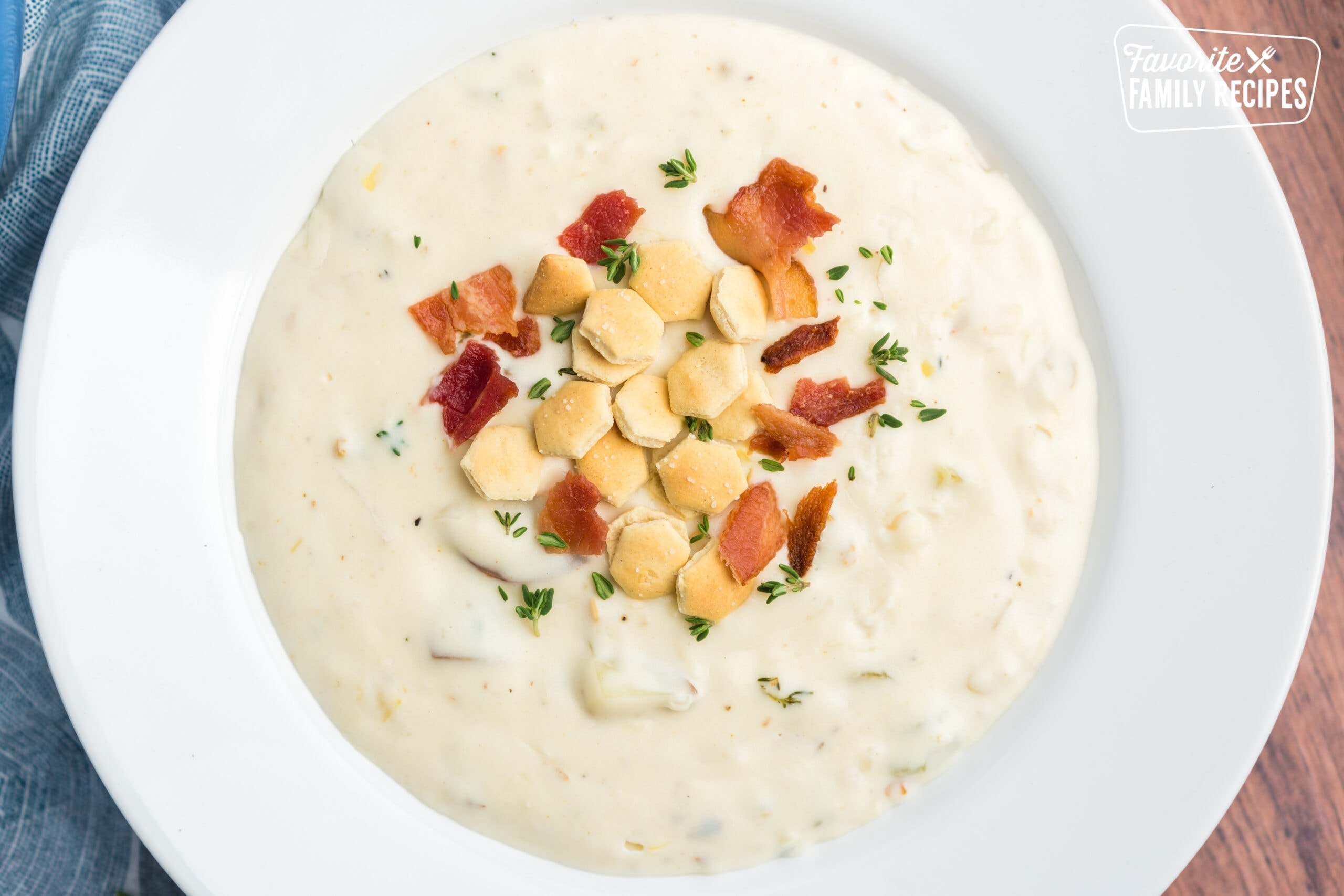 A bowl of the best clam chowder topped with oyster crackers and bacon