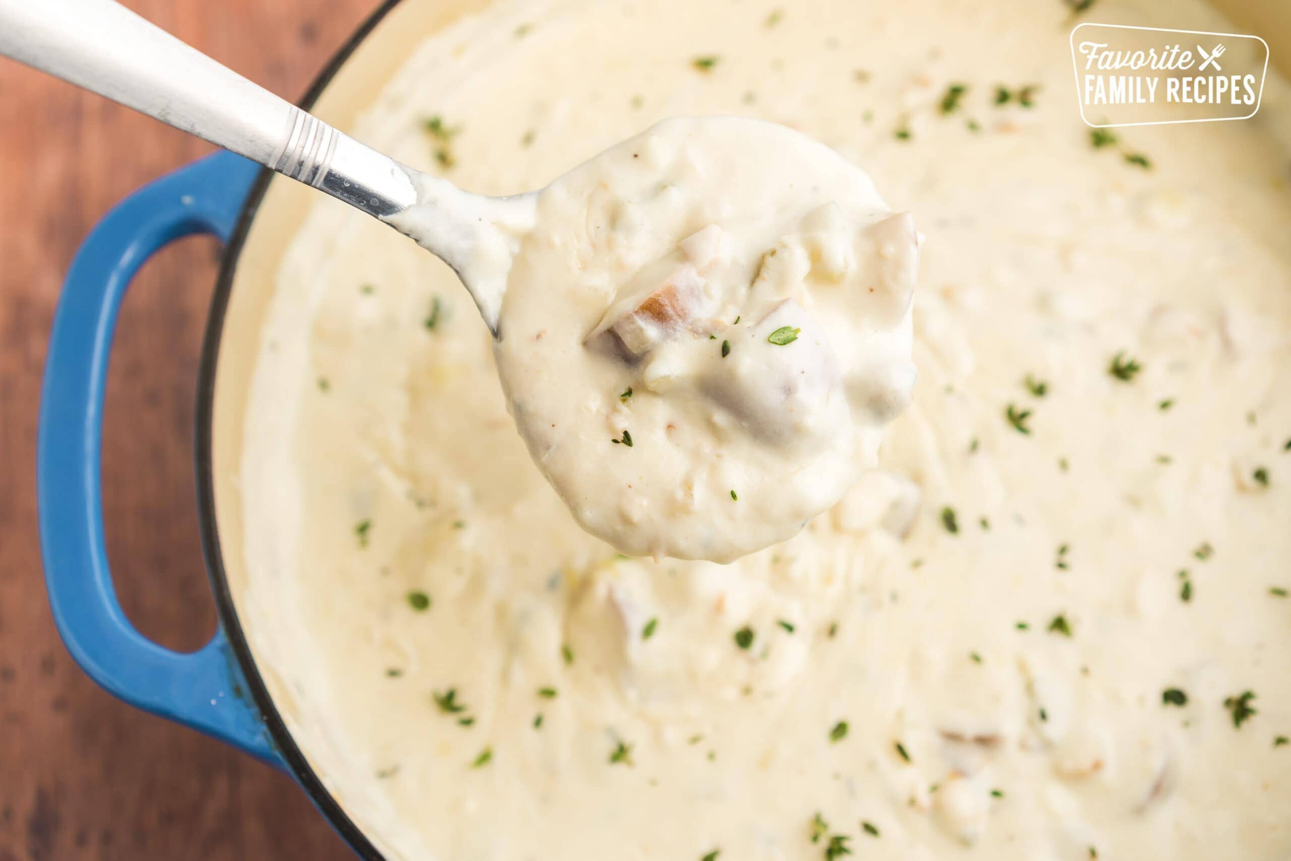 A ladle scooping up clam chowder from a blue pot