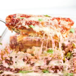 A piece of cheese manicotti being served out of a casserole dish