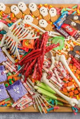 A halloween charcuterie board covered in candy and spooky treats with a skeleton in the middle.