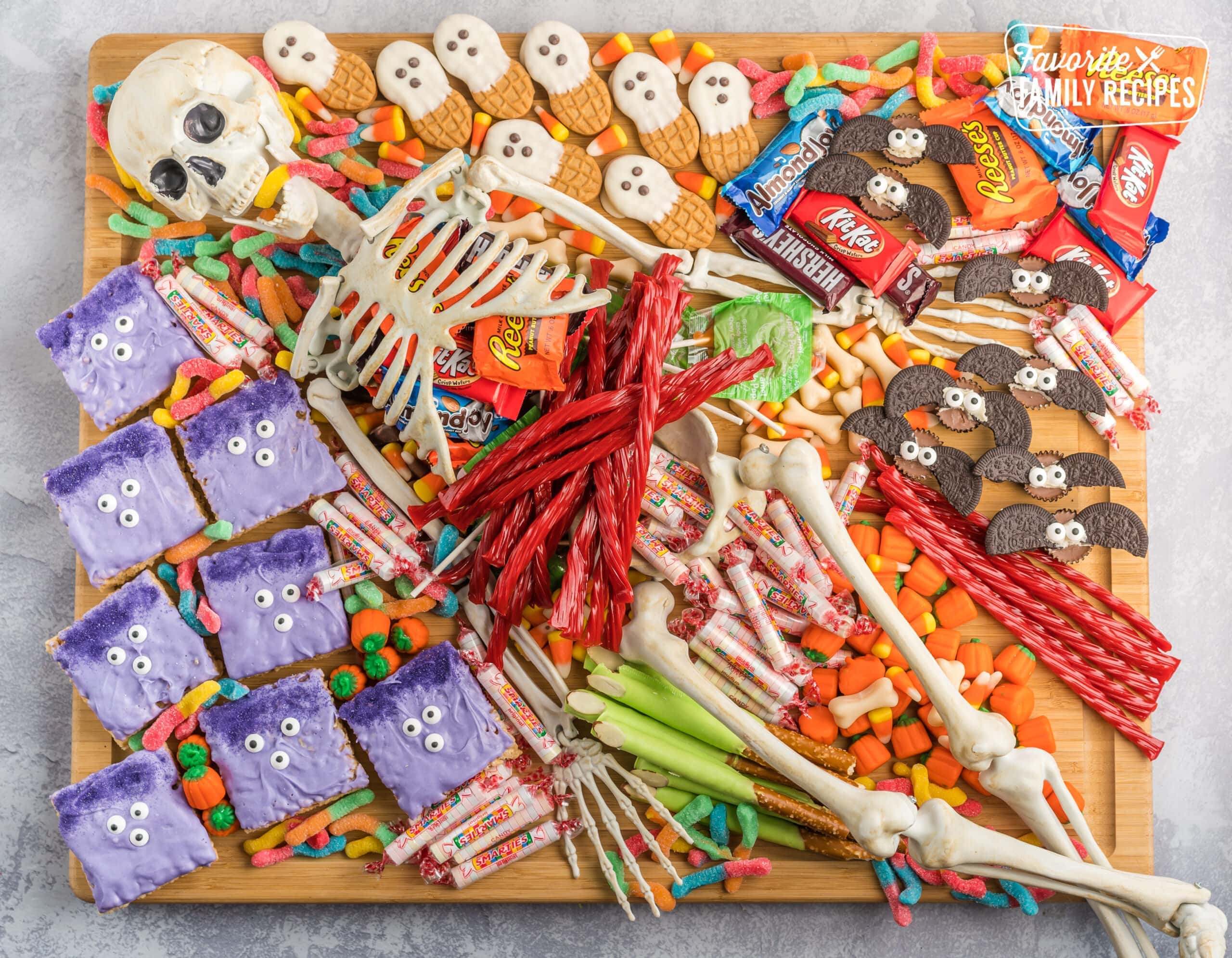 A halloween charcuterie board covered in candy and spooky treats with a skeleton in the middle.