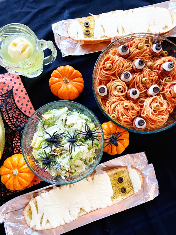 halloween spaghetti dinner with salad and garlic bread on a table
