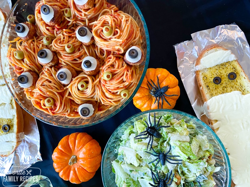 Halloween spaghetti in a bowl with salad and cheesy garlic bread