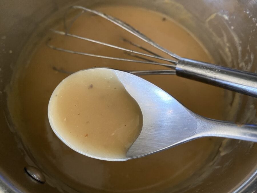 Spoon with poutine beef gravy.