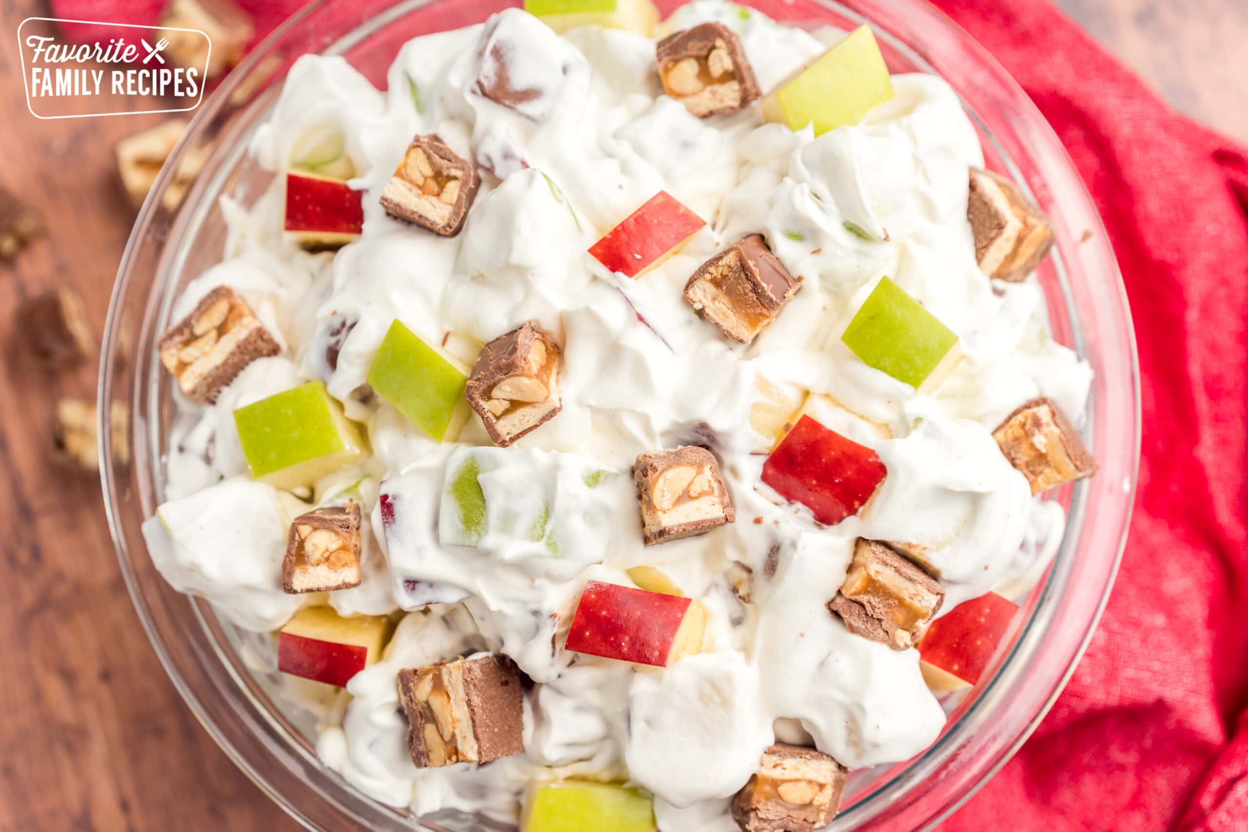Snickers Salad, also known as Snicker Apple Salad, is a salad the kids will actually be happy to eat! Tart, crispy apples and chewy, caramel-y Snickers bars are the perfect combination! Snickers salad in a glass bowl.