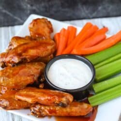 Portrait view of air fryer chicken wings on a plate with veggies and ranch dip