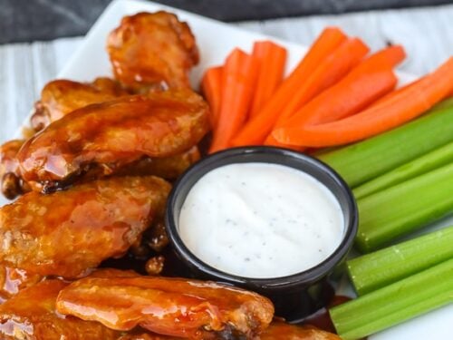 Portrait view of air fryer chicken wings on a plate with veggies and ranch dip