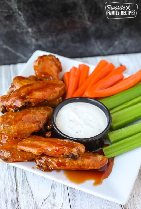 Portrait view of air fryer chicken wings on a plate with veggies and ranch dip