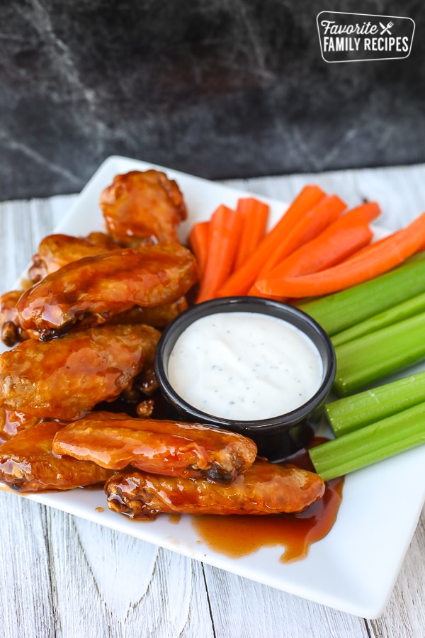 Portrait view of air fryer chicken wings on a plate with veggies and ranch dip