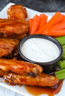 Side view of air fryer chicken wings on a plate with veggies and ranch dip