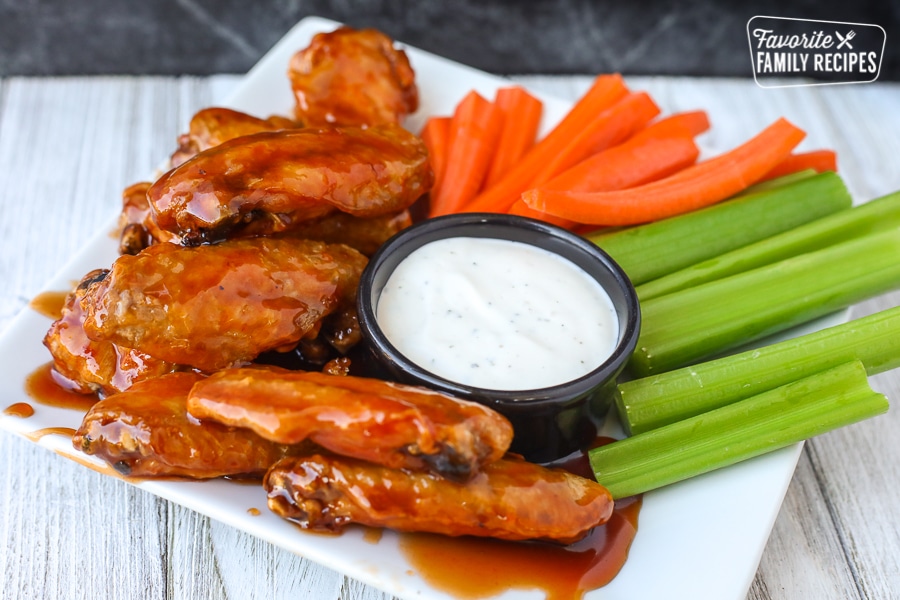 Side view of air fryer chicken wings on a plate with veggies and ranch dip