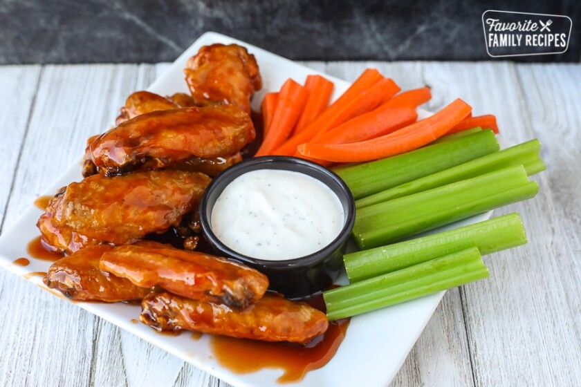 Wide view of air fryer chicken wings on a plate with veggies and ranch dip
